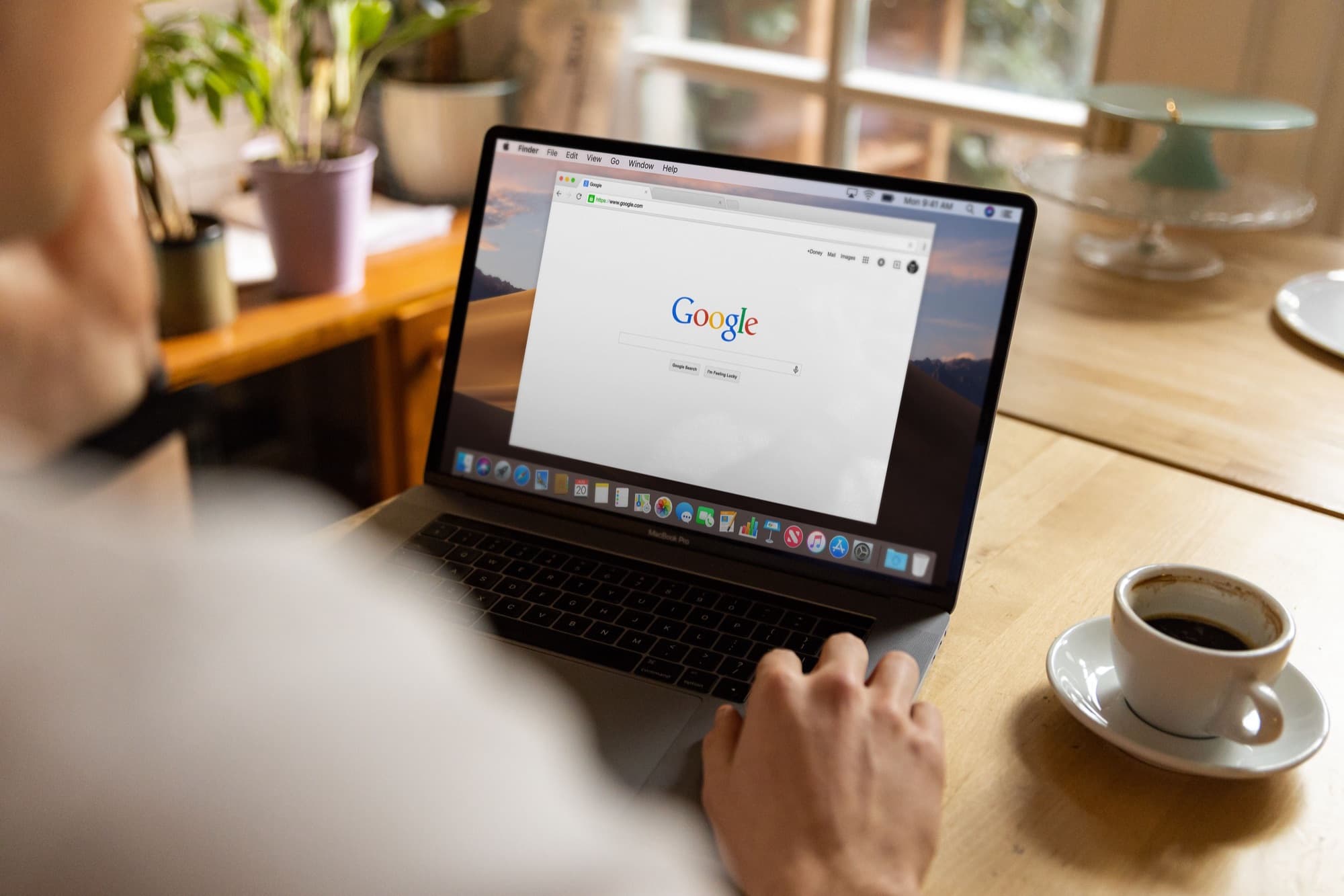 Someone at a kitchen table opening Google search on a laptop