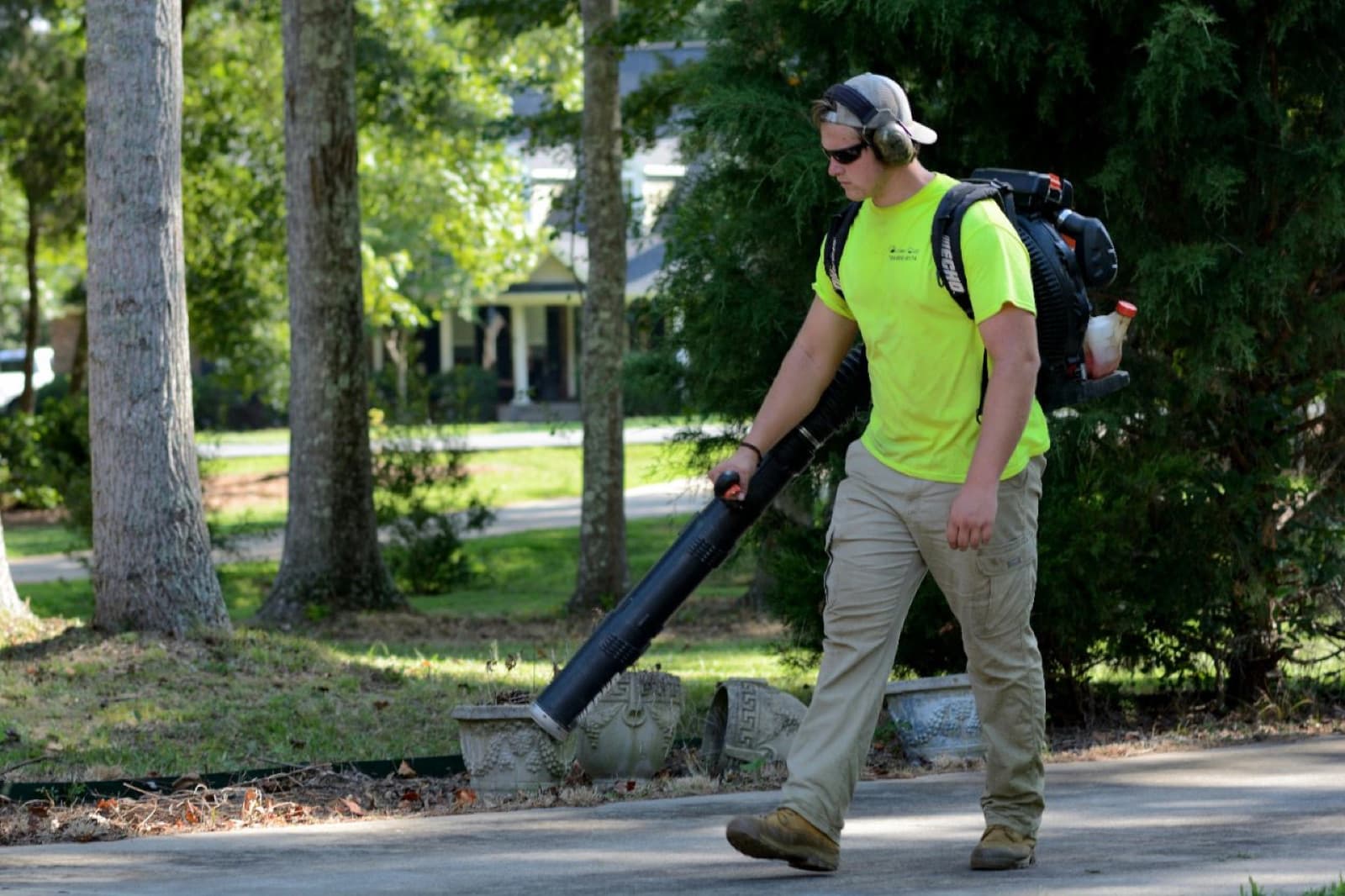 Lawn care technician clearing a driveway with a leaf blower